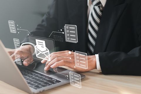 Foto: Mann vor Laptop mit schwebendem digitalen Brief über der Tastatur